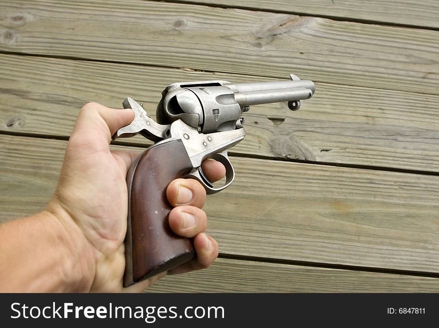 Cocked western style revolver being held in a hand pointed at a wall. Cocked western style revolver being held in a hand pointed at a wall