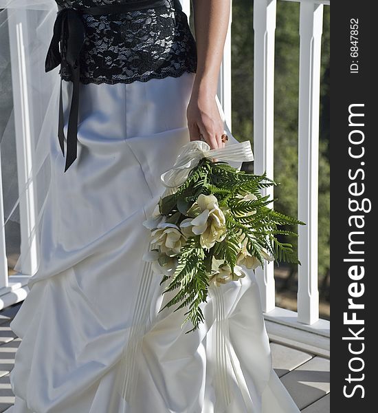 Bride with flowers standing outside on a deck