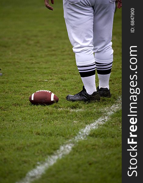 Legs of football official as he stands next to a football placed on the ground. Legs of football official as he stands next to a football placed on the ground