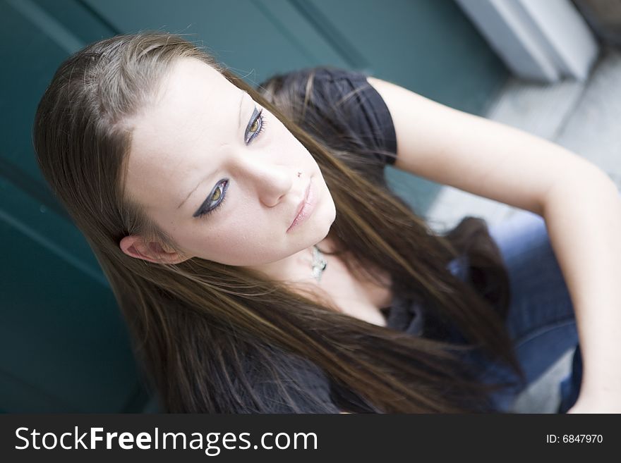 Young woman sitting patiently on a doorstep in thought, waiting for something to arrive. Young woman sitting patiently on a doorstep in thought, waiting for something to arrive.