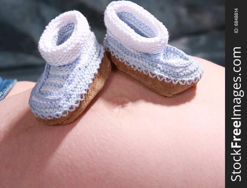 Baby booties sitting on top of the mommy baby belly