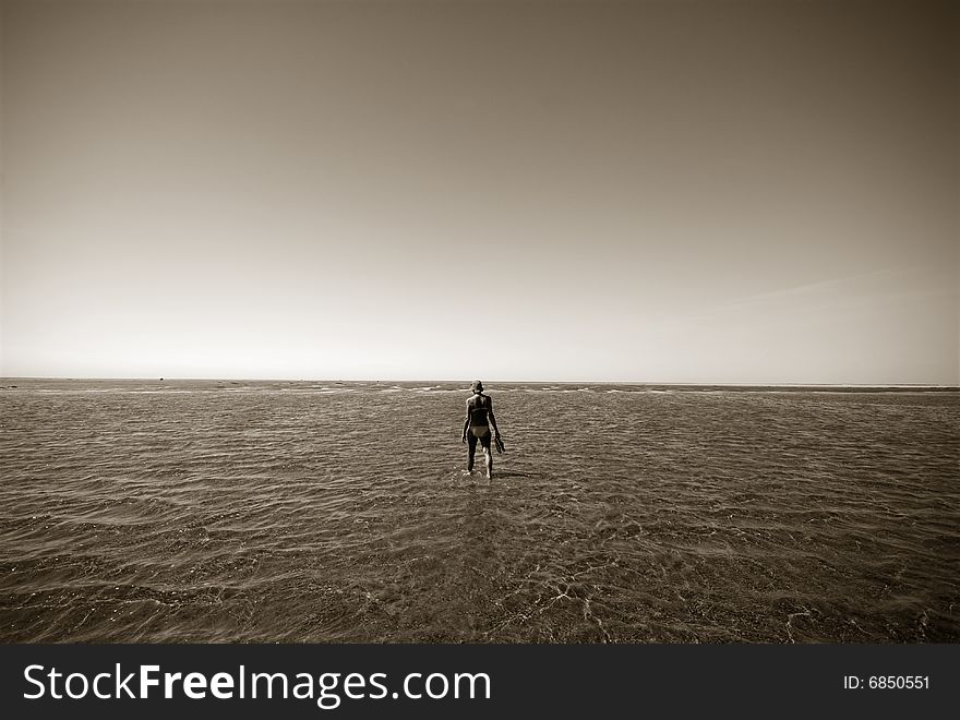 Walking to the Island.
Woman walking to Koresand in the water,  Low Tide Island in Denmark