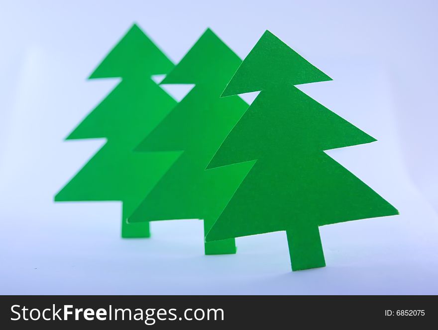 Three green paper spruces on white background