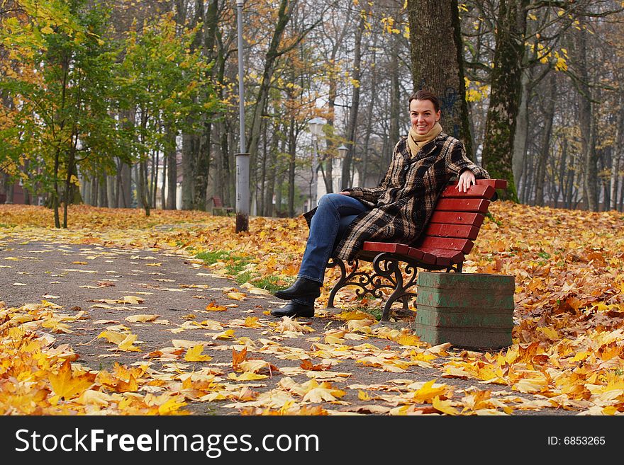 Young woman sitting on a bench in an autumn park