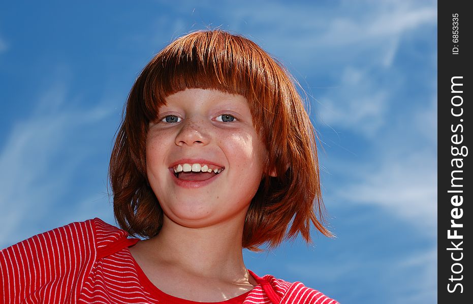 The girl in a red T-short with white strips laughs against the blue sky. The girl in a red T-short with white strips laughs against the blue sky