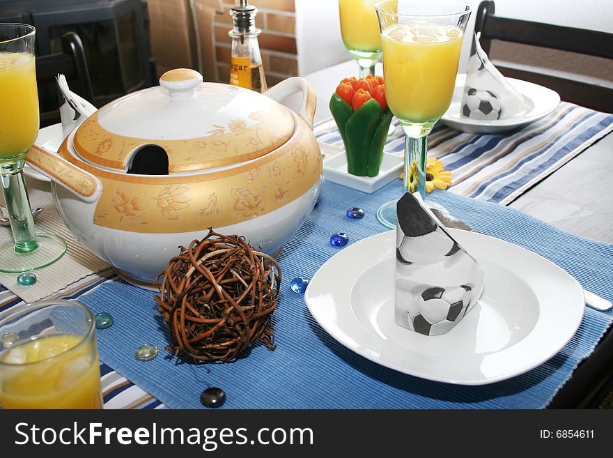 A eating table with table ware and juice. A eating table with table ware and juice