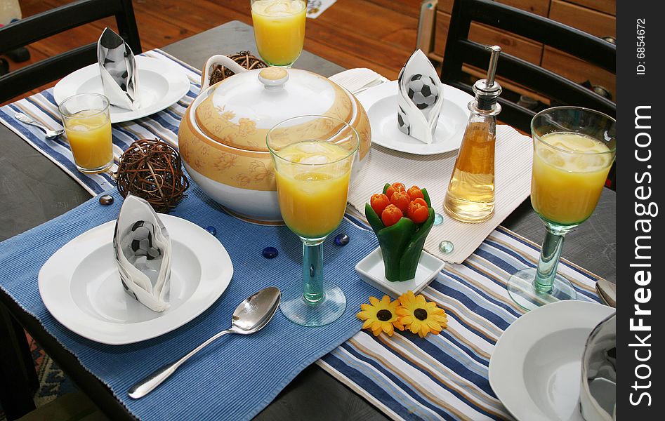 A eating table with table ware and juice. A eating table with table ware and juice