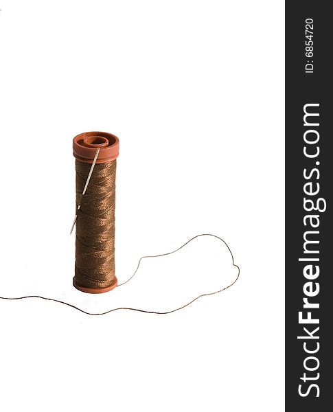 Brown thread isolated on a white background with a needle. Brown thread isolated on a white background with a needle