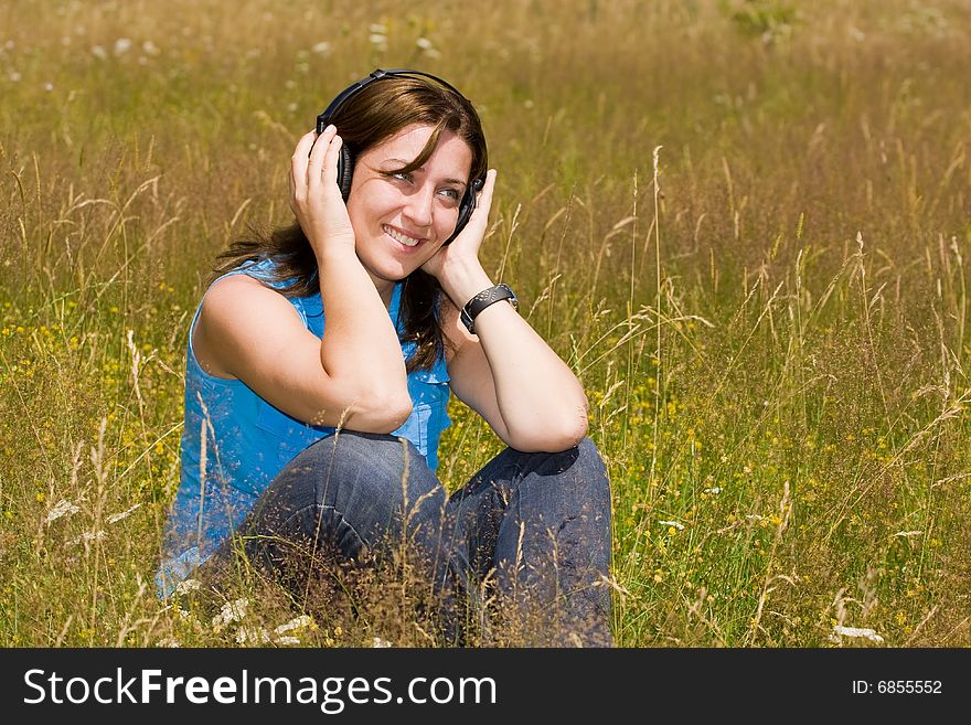 Attractive young woman listening music in a grass field. Attractive young woman listening music in a grass field