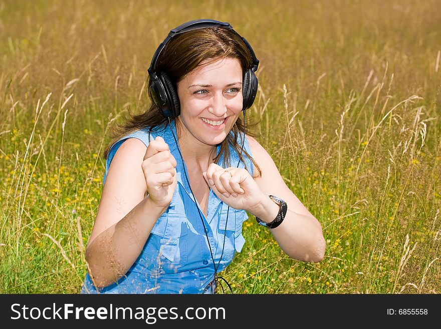 Attractive young woman listening music in a grass field. Attractive young woman listening music in a grass field