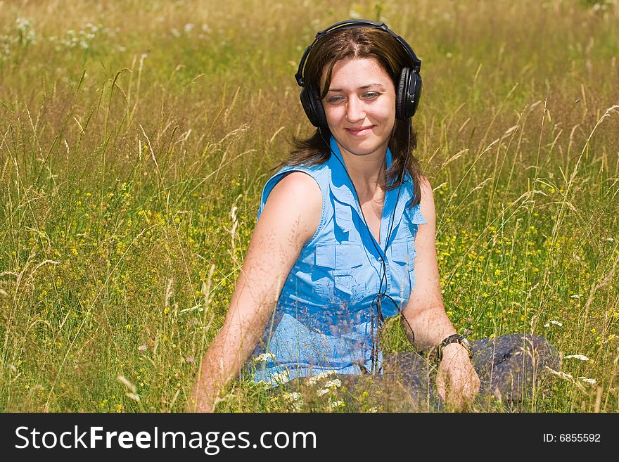 Attractive young woman listening music in a grass field. Attractive young woman listening music in a grass field