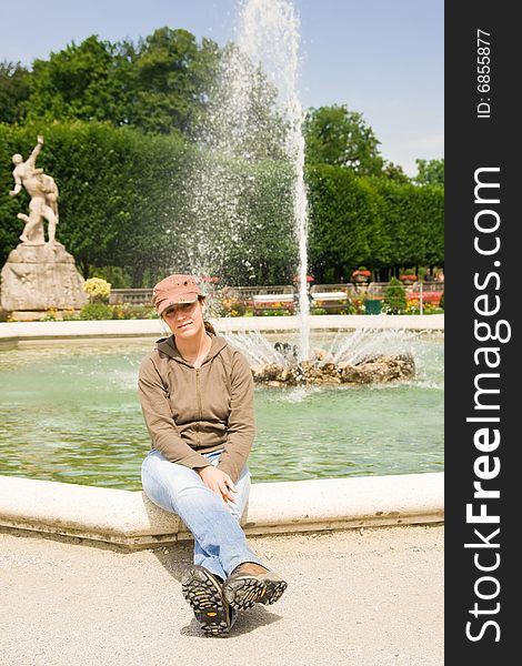 Girl sitting near a fountain in mirabell park, salzburg