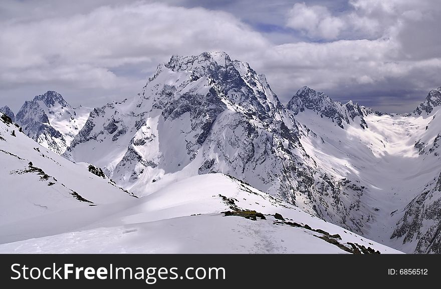 High-mountainous landscape shined by the sun through holes in clouds of a spot of light on a snow.Mountain track. 
Snow way.
Traces of the person in mountains. High-mountainous landscape shined by the sun through holes in clouds of a spot of light on a snow.Mountain track. 
Snow way.
Traces of the person in mountains.