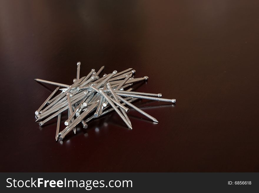 Anodized nails on the dark brown table top. Anodized nails on the dark brown table top