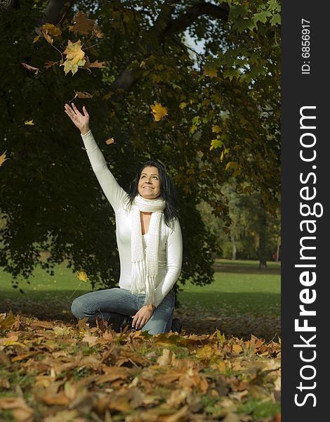 Girl having a lot of fun with falling leaves in autumn
