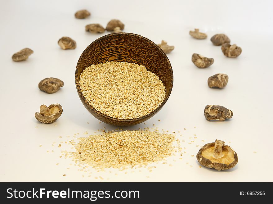 Sesame seeds in coconut bowl and dried shitake mushrooms isolated on white background. Sesame seeds in coconut bowl and dried shitake mushrooms isolated on white background