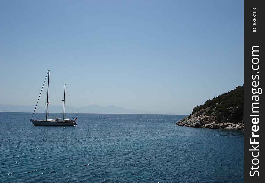 Small boat anchored in a gulf of a Mediterranean coast of Turkey on a perfect summer day. Small boat anchored in a gulf of a Mediterranean coast of Turkey on a perfect summer day