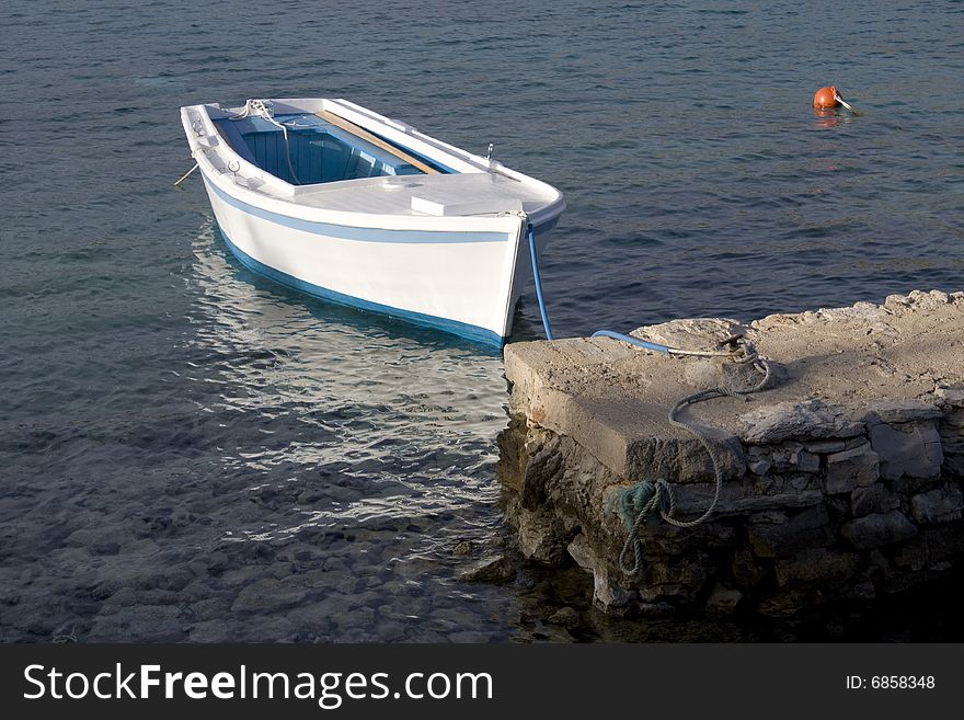 Anchored white wooden boat anchored on calm sea. Anchored white wooden boat anchored on calm sea