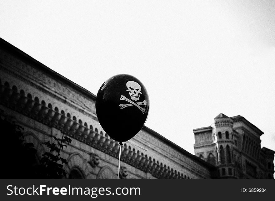 This black and white photograph represents a baloon with skull floating above boardwalk