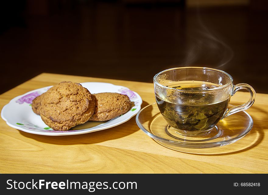 Glass cup with tea and biscuits on a plate closeup