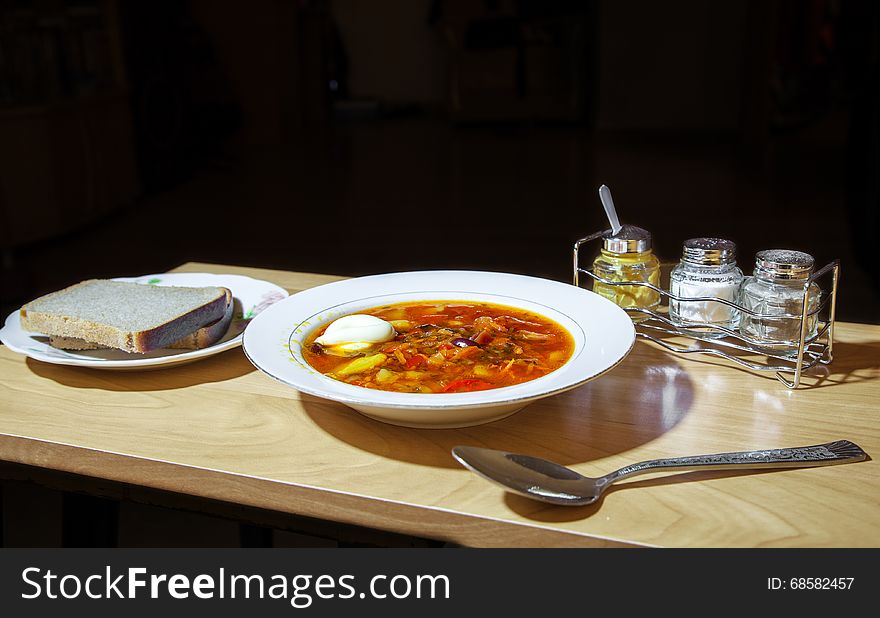 Plate of vegetable soup with two slices of bread on the table closeup