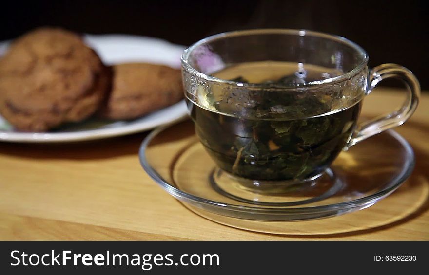 Glass cup with tea and biscuits on a plate closeup