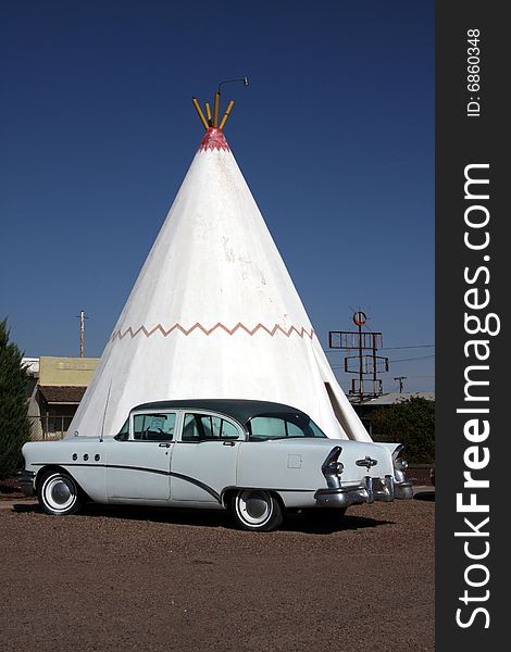 A wigwam bulding with period car