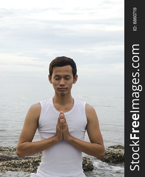 A young man meditating at the beach. A young man meditating at the beach