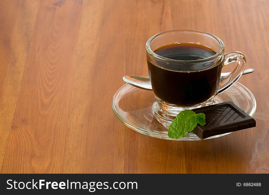 A coffee cup with black piece of dark chocolate