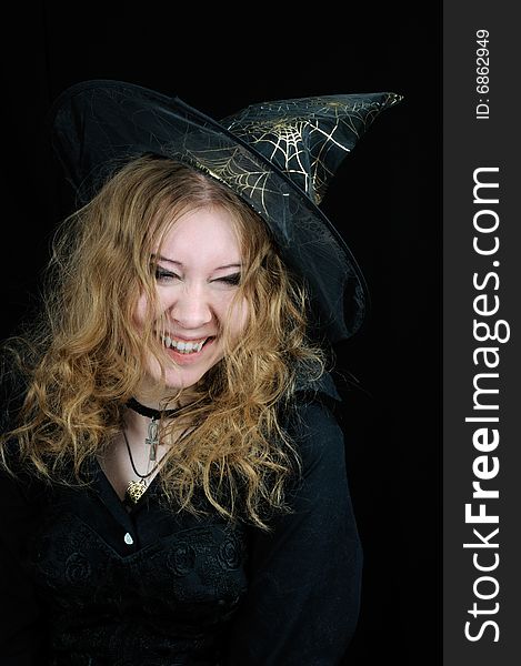 Cute young smiling halloween witch, on black background