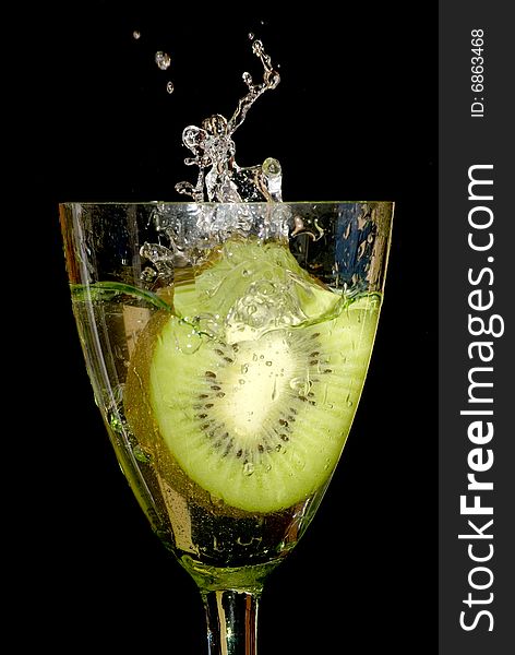 Piece of kiwi dropped in a glass of water. Piece of kiwi dropped in a glass of water