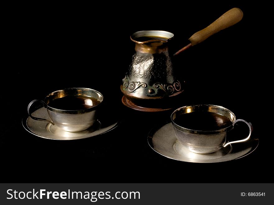 Two cups of coffee and coffee pot over black background