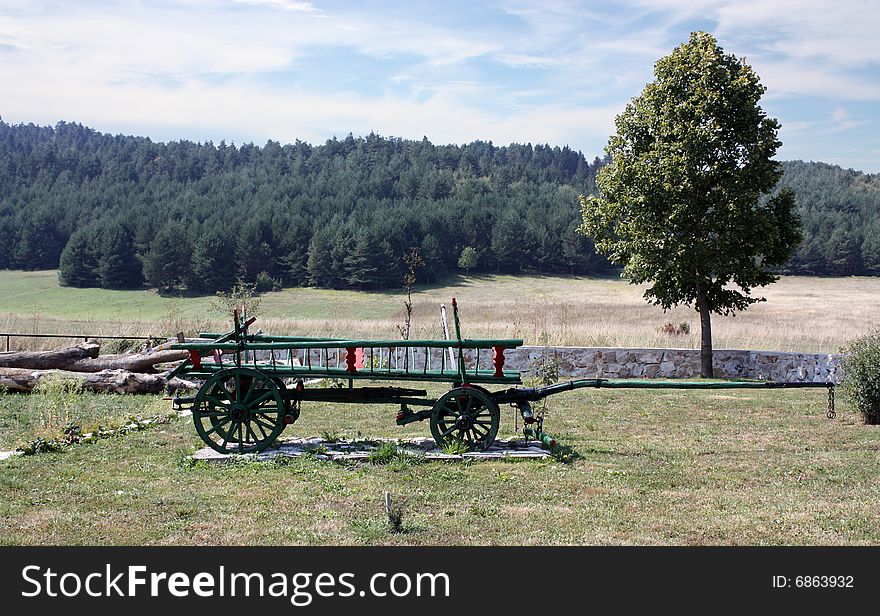 Wooden Cart against background a hill and woods