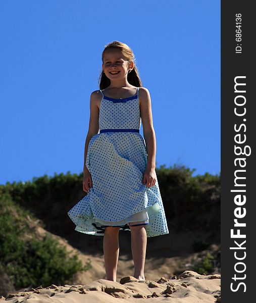 A white caucasian girl child playing on a sand dune on a hot summers day. A white caucasian girl child playing on a sand dune on a hot summers day