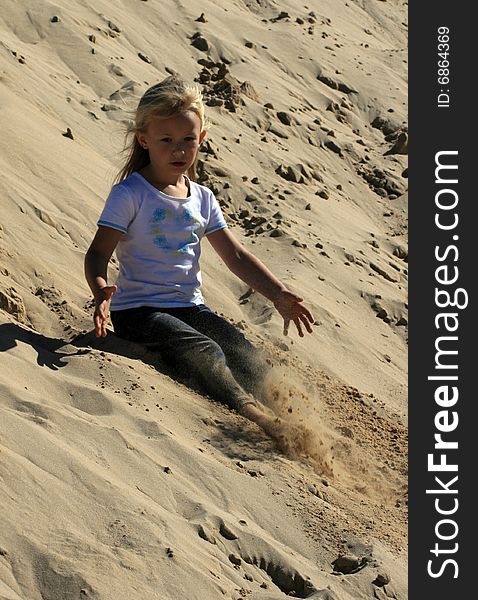 A white caucasian girl child playing on a sand dune on a hot summers day. A white caucasian girl child playing on a sand dune on a hot summers day