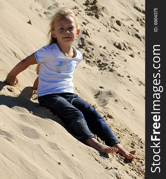 A white caucasian girl child playing on a sand dune on a hot summers day. A white caucasian girl child playing on a sand dune on a hot summers day