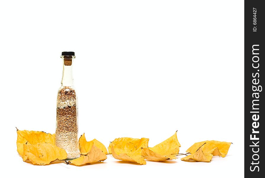 Bottle with groats and fall leafs isolated on white