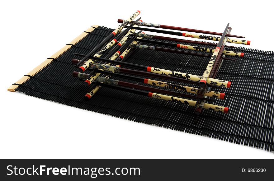 Chopsticks on the black bamboo mat. Square of the chopsticks.
. Chopsticks on the black bamboo mat. Square of the chopsticks.