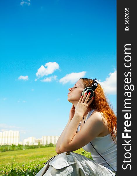 The girl in headphones listens to music in park. The girl in headphones listens to music in park