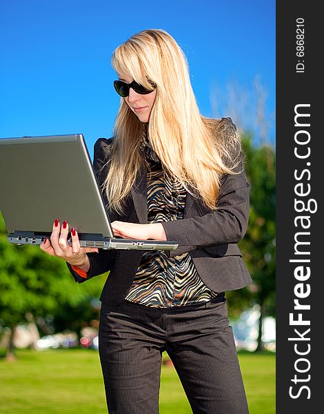 Young businesswoman in sunglasses standing with laptop. Young businesswoman in sunglasses standing with laptop