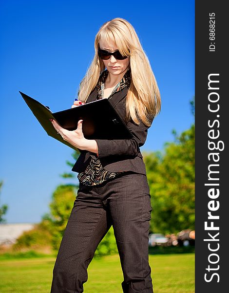 Blond businesswoman making a note in a folder. Blond businesswoman making a note in a folder