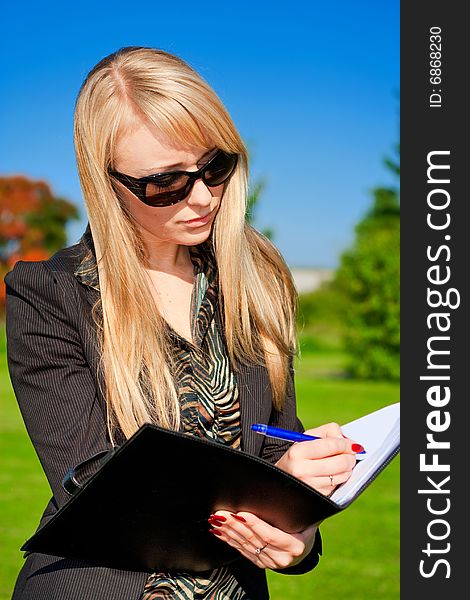 Blond businesswoman making a note in a folder. Blond businesswoman making a note in a folder