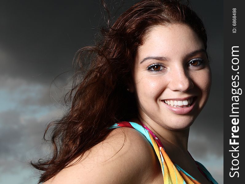 Young female smiling with cloudy sky background. Young female smiling with cloudy sky background