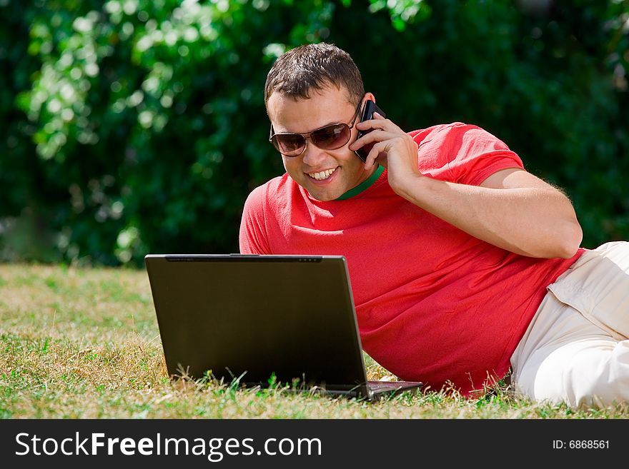 Young man working over a laptop computer and speaking phone