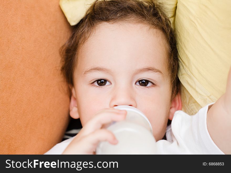 Small boy drinking milk from a bottle portrait