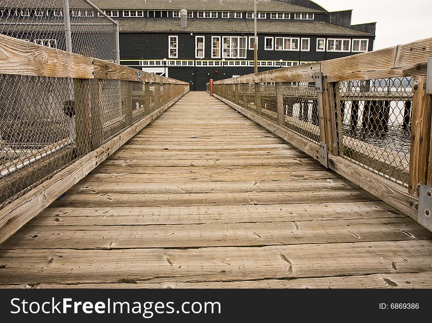 An old wooden plank walkway leading to a green coastal warehouse. An old wooden plank walkway leading to a green coastal warehouse