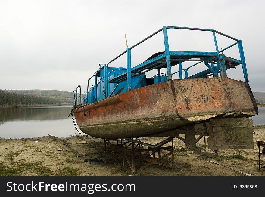 Abandoned steel ship, blue and red colored, rusted, back view