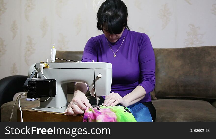 Young woman in blue blouse sews on the sewing machine. Young woman in blue blouse sews on the sewing machine