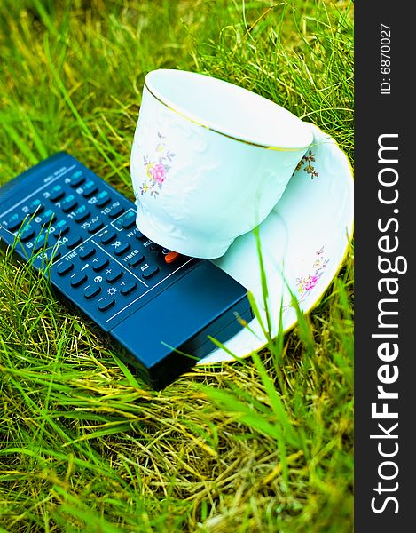 Photo of remote and cup on the grass. Photo of remote and cup on the grass