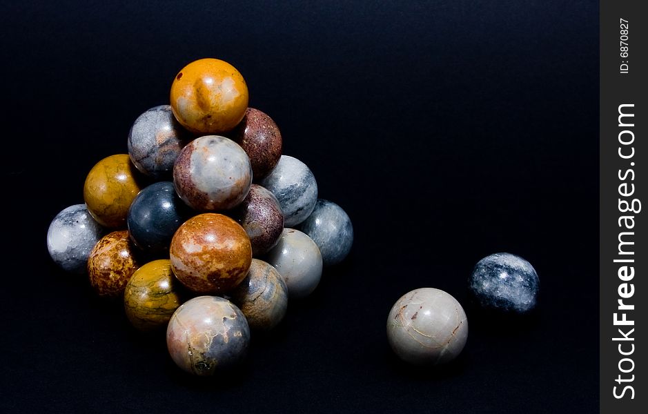 Interesting marble spheres arranged in a pyramid and isolated on a black background. Interesting marble spheres arranged in a pyramid and isolated on a black background.
